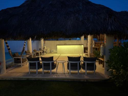a patio with chairs and a table with a large straw umbrella at Villa Marena Hotel Boutique in Coyuca