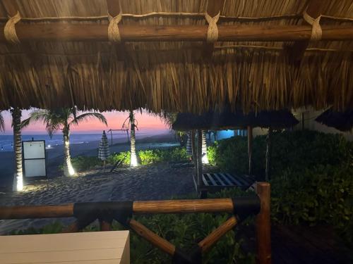 a view of a beach with a straw umbrella at Villa Marena Hotel Boutique in Coyuca