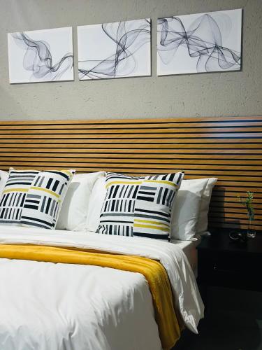 a bedroom with a white bed with four pictures on the wall at Impèrio Boutique Guest Lodge in Siyabuswa