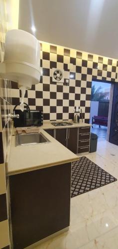 a kitchen with a sink and a checkered wall at عوالي الصفا للضّيافه in Buraydah