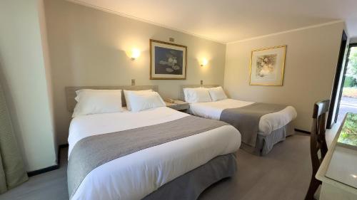 a hotel room with two beds and a window at Hotel Villa El Descanso Express in Curicó