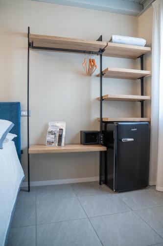 a room with a bed and a desk and a refrigerator at ES Rooms and Apartments in Nago-Torbole