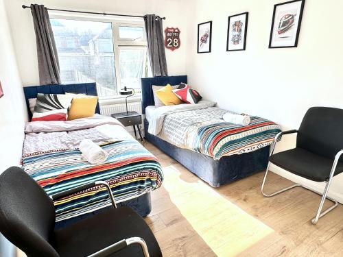 a bedroom with two beds and a chair and a window at 3 bedroom entire house sleeps 8 twin beds near Coventry University City Center driveway Parking in Coventry