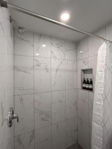 a bathroom with a shower with white marble walls at Hotel La Residence du Voyageur in Montréal
