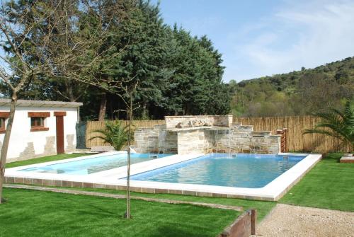 a swimming pool in a yard with a stone wall at Finca Avellaneda in Navahondilla