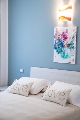a bed with white pillows and a painting on the wall at ES Rooms and Apartments in Nago-Torbole