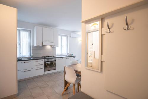 a kitchen with white cabinets and a table with a chair at ES Rooms and Apartments in Nago-Torbole