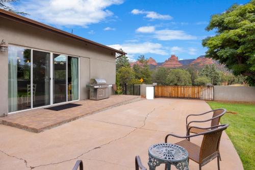 a patio with chairs and a grill with mountains in the background at Sedona Uptown Gem!Large yard w grass and shade trees! Views!! NEW! BARREL SAUNA!!! Close to trails, walk to Uptown Sedona, restaurants and shopping in Sedona
