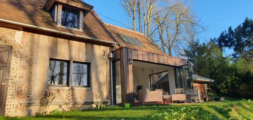 une ancienne maison en briques avec des chaises sur la terrasse couverte dans l'établissement Maison Normande au bord de rivière avec spa et sauna, à Rugles