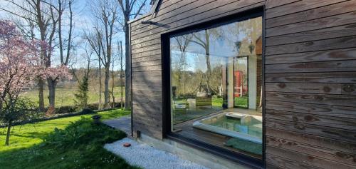une maison avec une grande fenêtre sur le côté dans l'établissement Maison Normande au bord de rivière avec spa et sauna, à Rugles