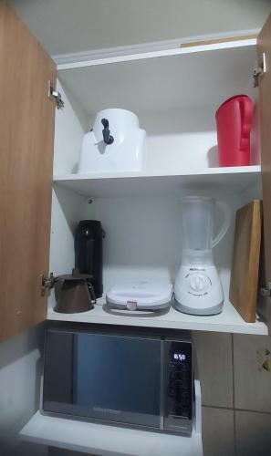 a kitchen with a microwave and a blender on a shelf at Brisa do Mar in Caraguatatuba