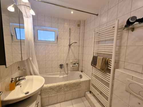 a white bathroom with a tub and a sink at Sonnenschein1L mit Terrasse und Garten in Friedrichshafen