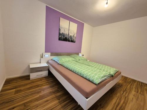 a bedroom with a bed and a purple wall at Sonnenschein1L mit Terrasse und Garten in Friedrichshafen