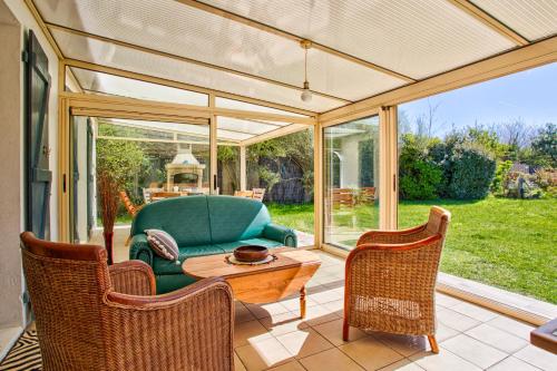 une véranda avec une table et des chaises dans l'établissement Gîte L'Escapade - face au golf et à 3 min de la plage de Barneville, à Barneville-Plage