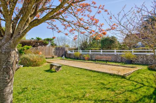 un jardin avec une clôture blanche et un banc dans l'établissement Gîte L'Escapade - face au golf et à 3 min de la plage de Barneville, à Barneville-Plage