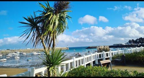 une plage avec des bateaux dans l'eau et une clôture blanche dans l'établissement Studio proche de la mer, à Saint-Quay-Portrieux