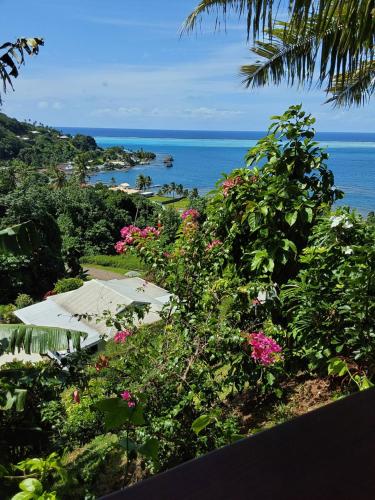 a view of the ocean with an umbrella and flowers at Faré Mahi Mahi in Uturoa