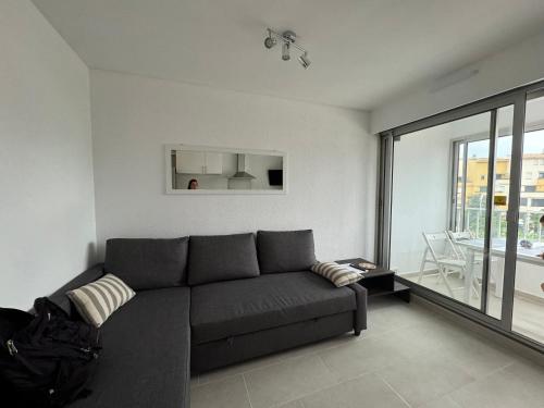 - un salon avec un canapé gris et une grande fenêtre dans l'établissement appartement centre port, au Cap d'Agde
