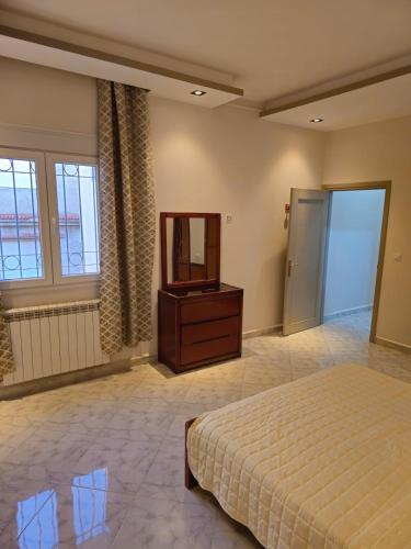 ein Schlafzimmer mit einem Bett, einer Kommode und einem Spiegel in der Unterkunft Appartement résidence EL-HANA in Tlemcen