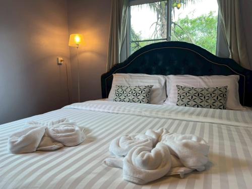 two towels on a bed with a window at Coco farm stay Suanphueng in Ratchaburi