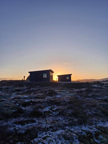 a house in a field with the sunset in the background at Bygghamar in Stykkishólmur