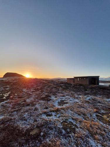 a field with the sun setting in the distance at Bygghamar in Stykkishólmur