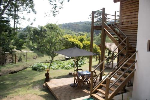 a wooden deck with a staircase and an umbrella at Pousada Recanto da Pantera in Cunha