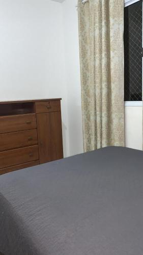 a bedroom with a bed and a dresser and a window at Aconchego Da Diane - Enseada in Guarujá