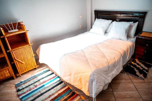 a bedroom with a large white bed and a rug at Imsouane petitsurfer SurfCamp in Imsouane