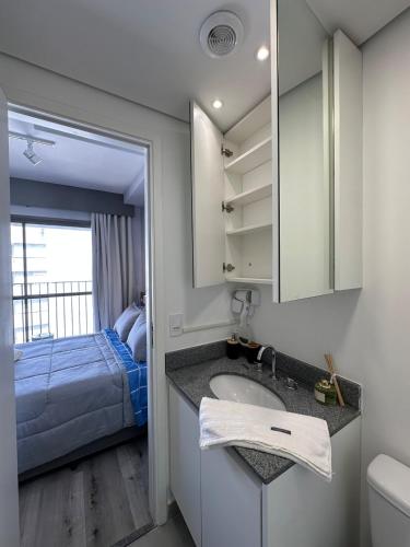 a bathroom with a sink and a bedroom with a bed at Liberdade Loft & Comfort in São Paulo