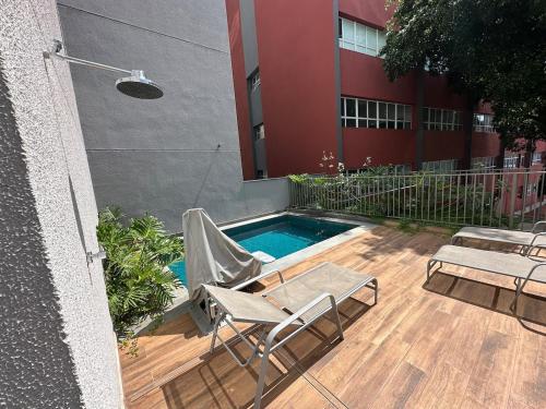 une terrasse avec des chaises et une piscine en face d'un bâtiment dans l'établissement Liberdade Loft & Comfort, à São Paulo