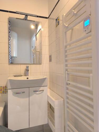 une salle de bain blanche avec un lavabo et un miroir dans l'établissement La Lanterne, à Villers-sur-Mer