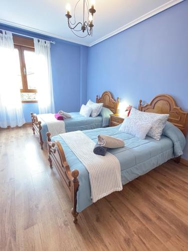two beds in a room with blue walls and wooden floors at Casa Pilar Casa Llara, En el paraíso, cerca de todo in Ujo