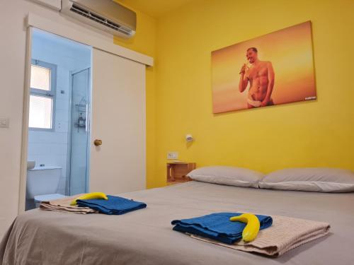 a yellow room with a bed with two towels on it at Maracuya House - Men Only in Torremolinos