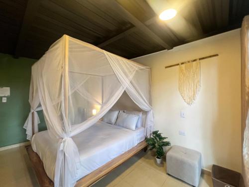 a bedroom with a canopy bed with white sheets and pillows at Rincon de la Sierra Minca in Minca