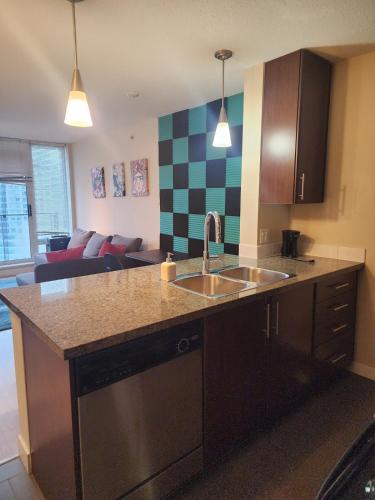 a kitchen with a sink and a living room at Modern High-Rise 1 Bedroom Condo with water view near stadiums in Vancouver