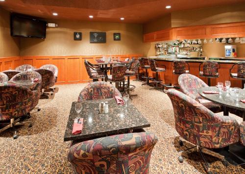 a restaurant with tables and chairs and a bar at Holiday Inn Hinton by IHG in Hinton