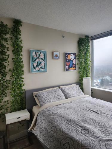 a bedroom with a bed and a window with plants at Modern High-Rise 1 Bedroom Condo with water view near stadiums in Vancouver