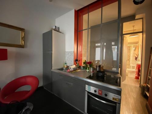 une cuisine avec un comptoir et une chaise rouge dans l'établissement Wonderful and spacious flat in Paris Opera Montmartre, à Paris