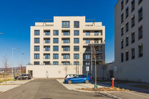 a blue car parked in a parking lot in front of a building at BNB Panorama Bory Penthouse in Bratislava