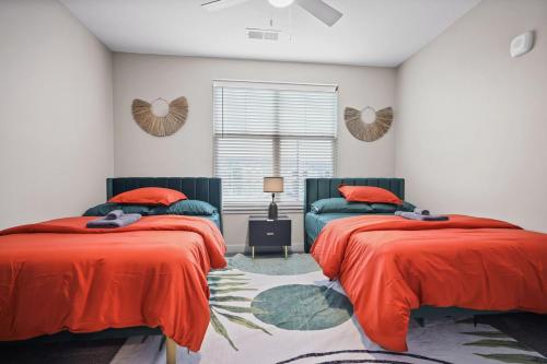 a bedroom with two beds with orange sheets and a window at IRIE Living, Replenish Kg 2Bd Gym Pool BRAND NEW in Whitestown
