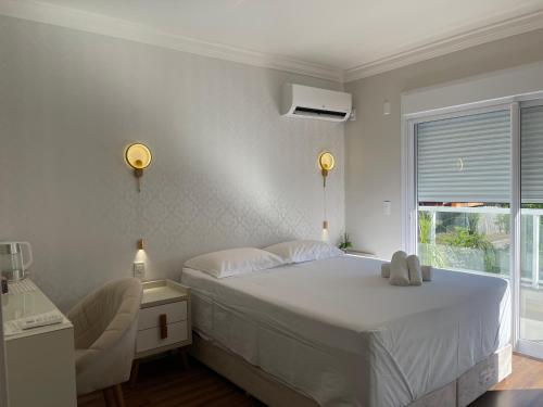 a white bedroom with a bed and a window at Dolce Vita in Porto Belo