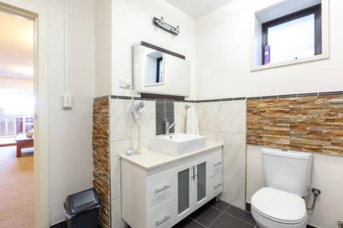 a bathroom with a white toilet and a sink at Beachfront Apartment Blackmans Bay in Kingston Beach