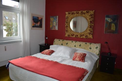 Schlafzimmer mit einem Bett mit einer roten Wand und einem Spiegel in der Unterkunft Haus zum Rhein in Lahnstein