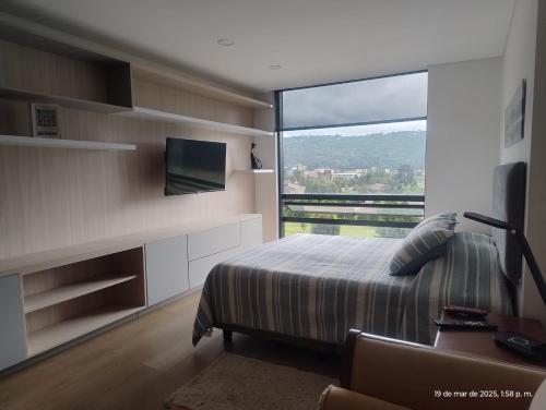 a bedroom with a bed and a large window at Apartaestudio, hermosa vista a la Sabana in Chía