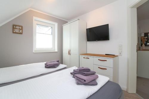 a bedroom with two beds and a flat screen tv at Hafenbrise in Greetsiel