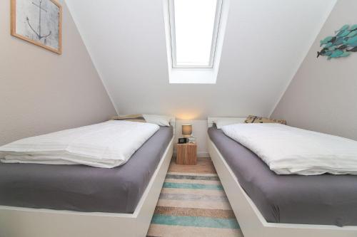 two beds in a attic bedroom with a window at Hafenbrise in Greetsiel