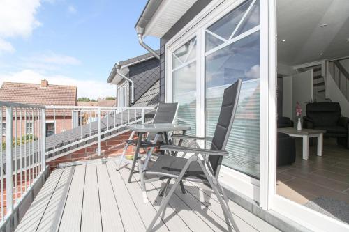 a balcony with two chairs and a table on it at Hafenbrise in Greetsiel