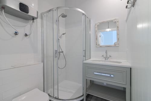 a white bathroom with a shower and a sink at Prawdziwa Jurata in Jurata