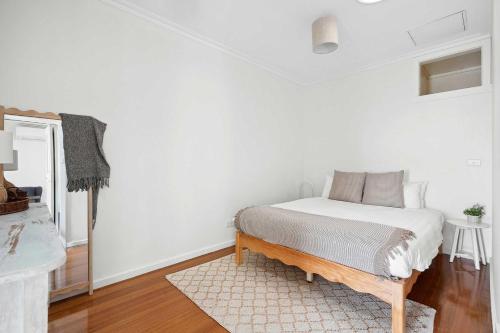 Geelong WestにあるCosy Townhouse in the Heart of Geelong Westの白いベッドルーム(ベッド1台、ラグ付)